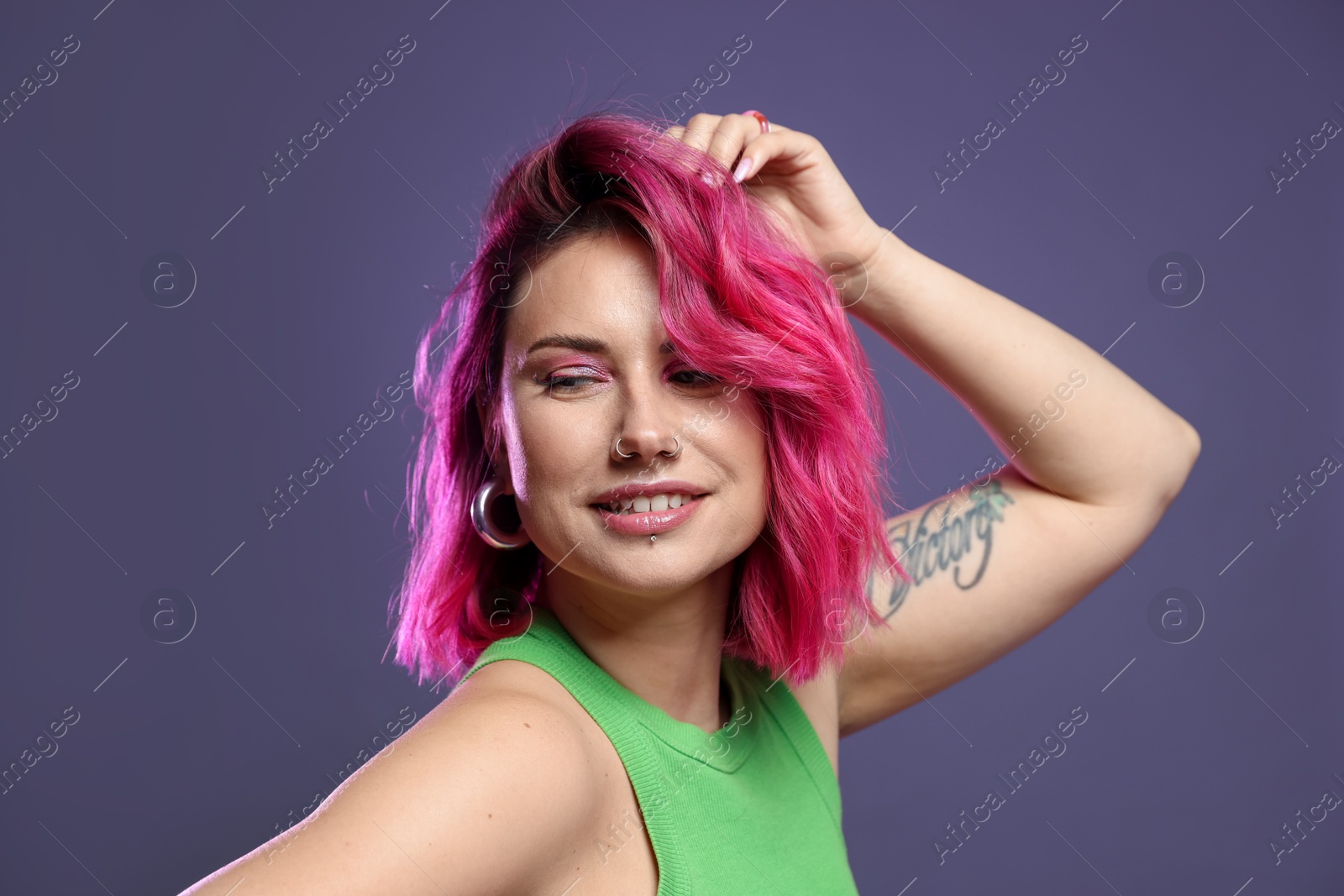 Beautiful woman with pink dyed hair on violet background Photo of Beautiful woman with pink dyed hair on violet background