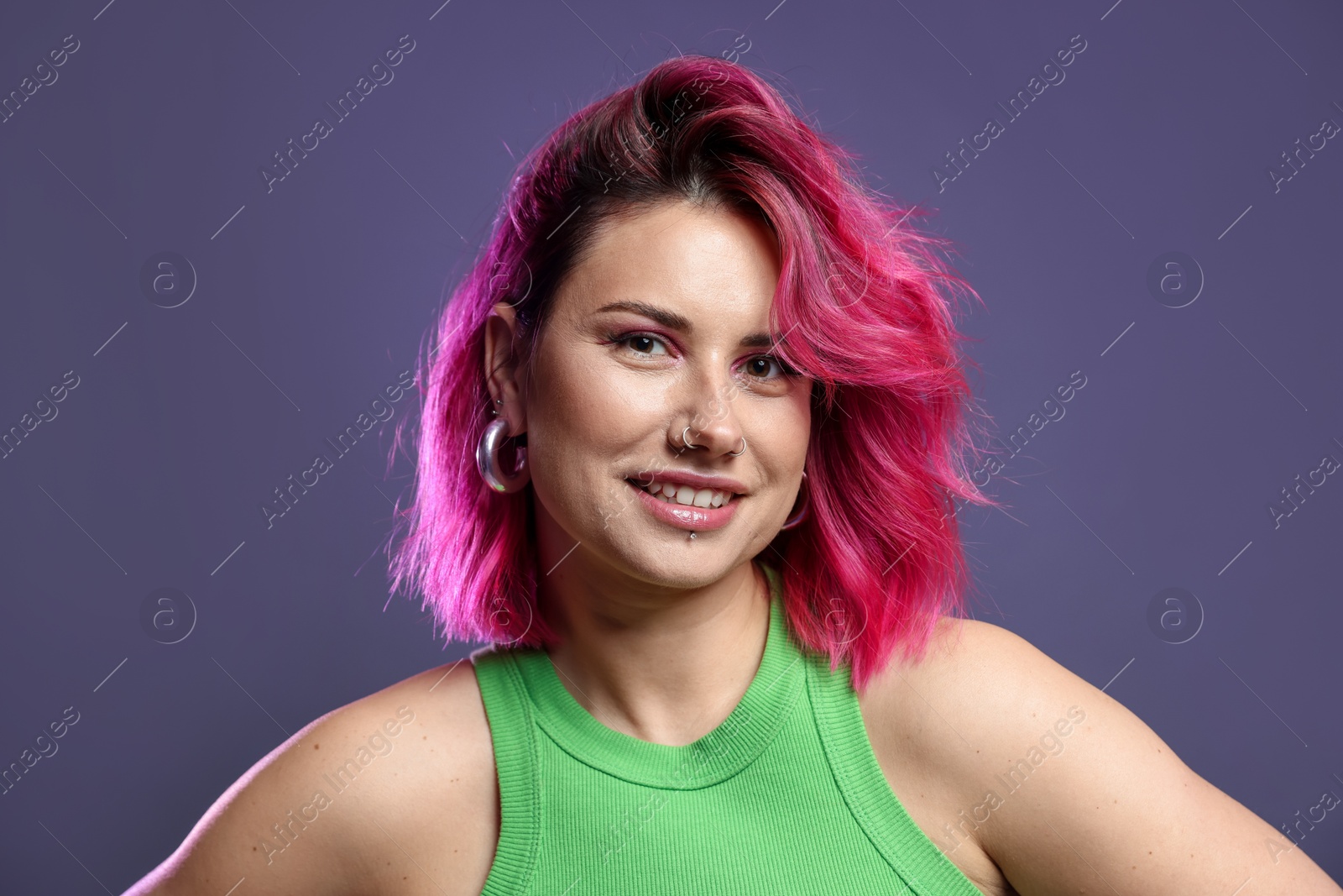 Beautiful woman with pink dyed hair on violet background Photo of Beautiful woman with pink dyed hair on violet background