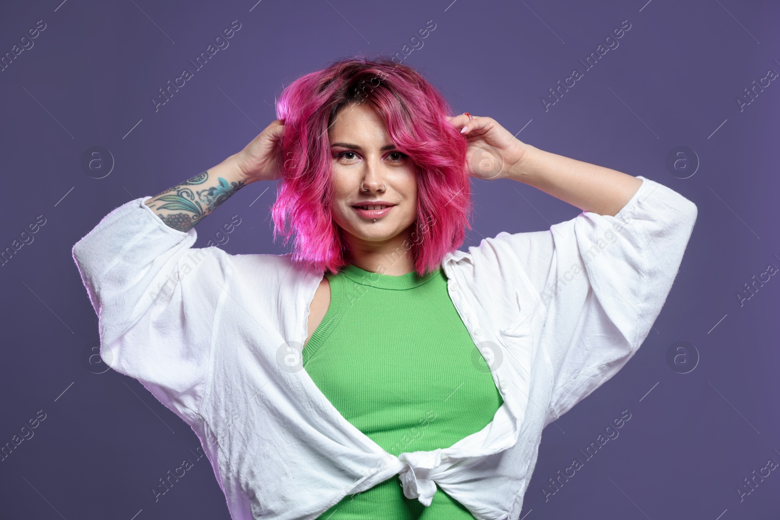 Beautiful woman with pink dyed hair on violet background Photo of Beautiful woman with pink dyed hair on violet background