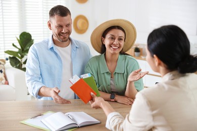 Photo of Happy couple planning vacation with travel agent at wooden table in office