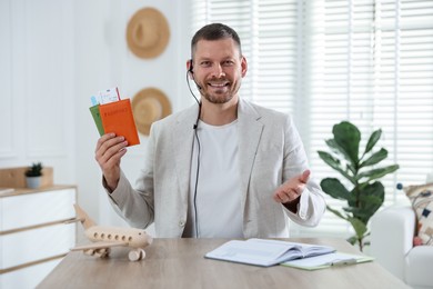 Photo of Travel agent with passports and tickets at wooden table in office