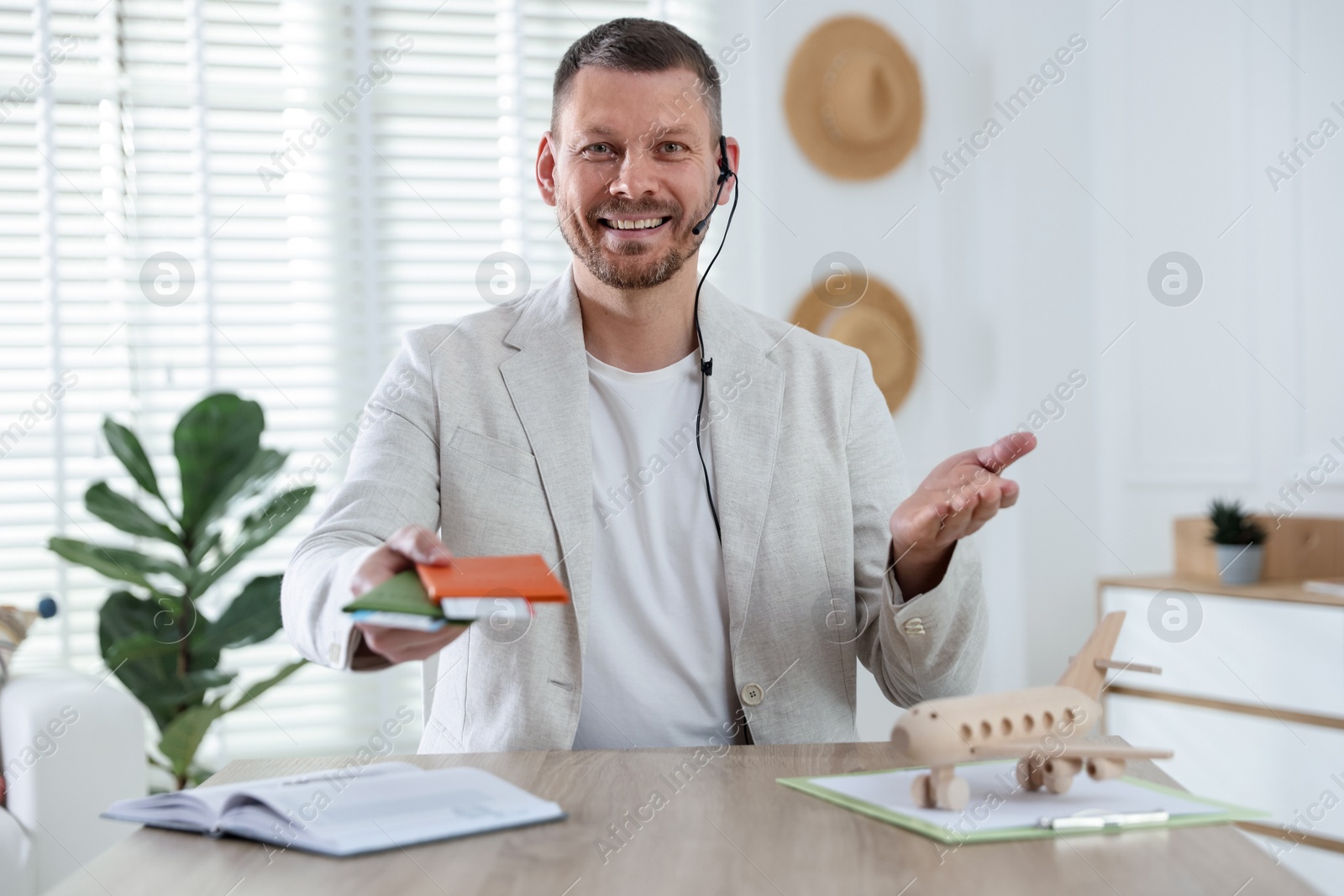 Travel agent with passports and tickets at wooden table in office Photo of Travel agent with passports and tickets at wooden table in office