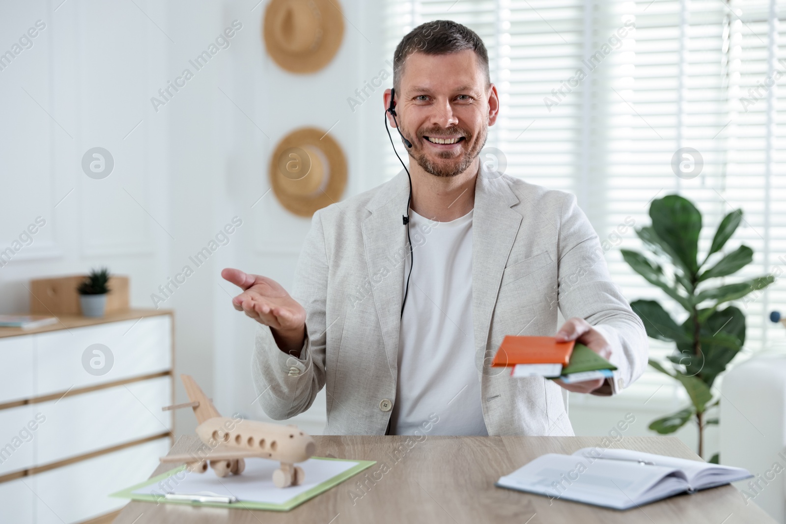 Travel agent with passports and tickets at wooden table in office Photo of Travel agent with passports and tickets at wooden table in office