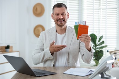 Photo of Travel agent with passports and tickets at wooden table in office