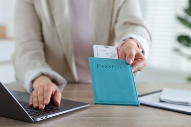 Photo of Travel agent with passport and ticket at wooden table in office, closeup
