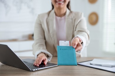 Photo of Travel agent with passport and ticket at wooden table in office, closeup
