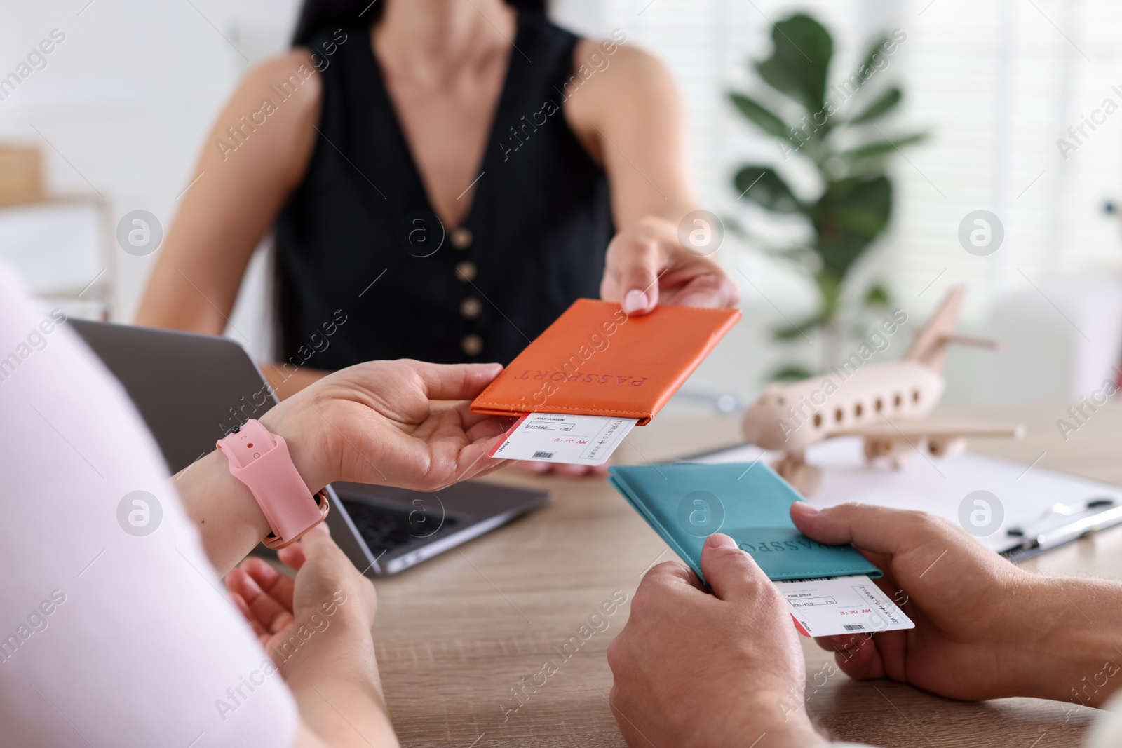 Travel agent giving passports with tickets to couple at wooden table in office, closeup Photo of Travel agent giving passports with tickets to couple at wooden table in office, closeup