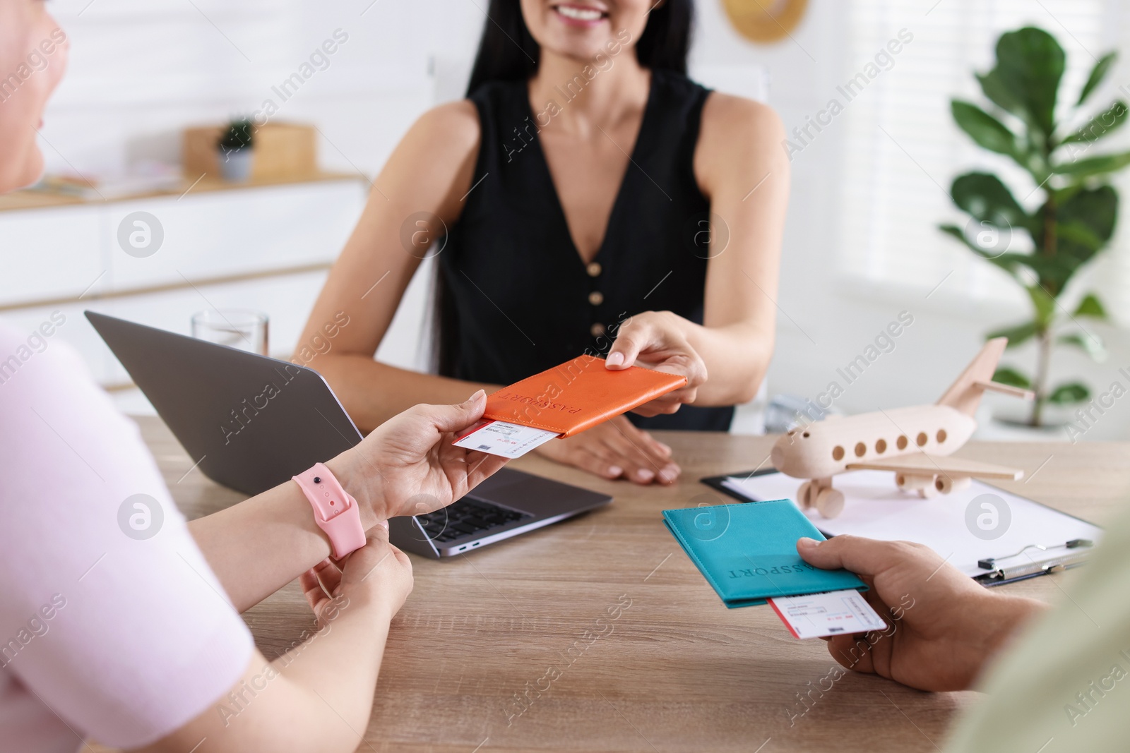 Travel agent giving passports with tickets to couple at wooden table in office, closeup Photo of Travel agent giving passports with tickets to couple at wooden table in office, closeup