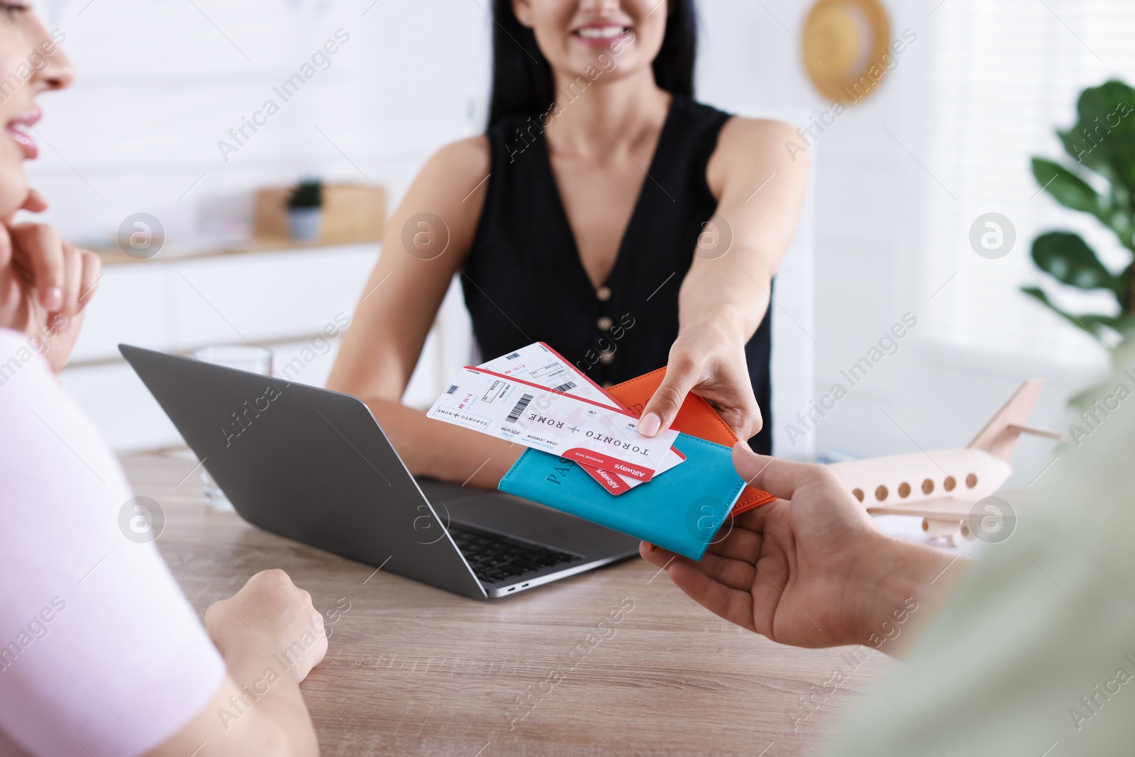 Travel agent giving passports with tickets to couple at wooden table in office, closeup Photo of Travel agent giving passports with tickets to couple at wooden table in office, closeup