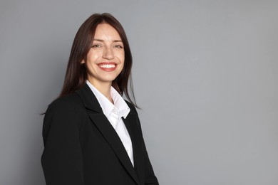 Photo of Happy woman in suit on grey background, space for text