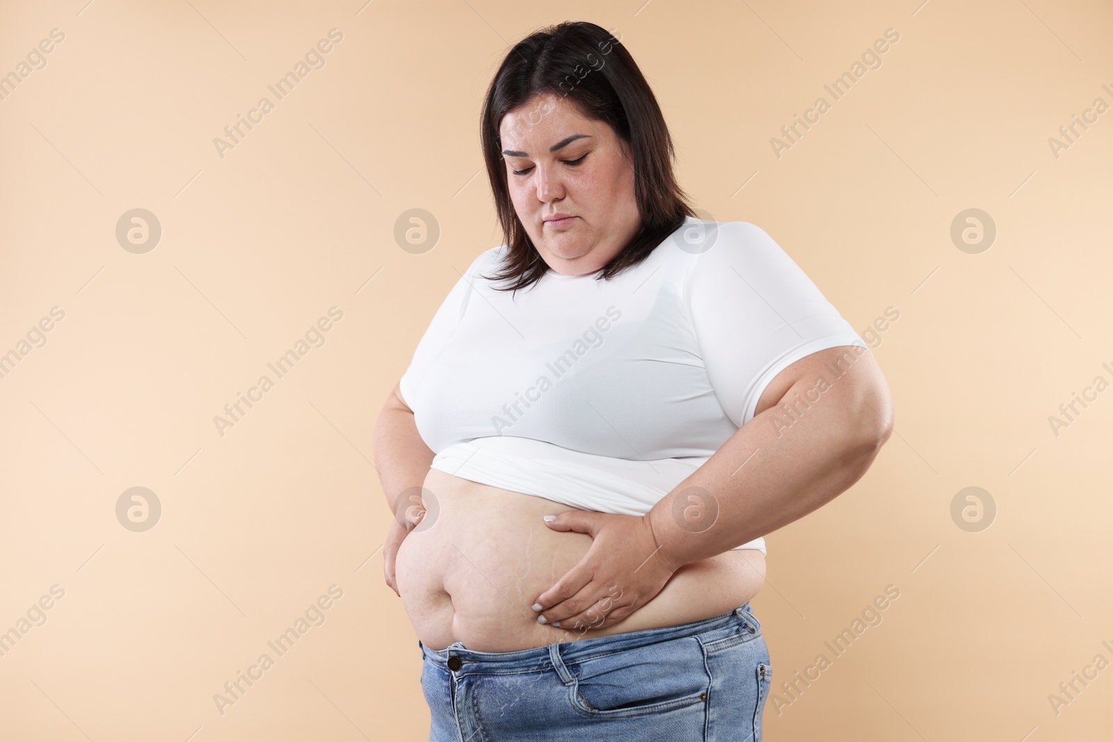 Woman with excessive belly fat on beige background Photo of Woman with excessive belly fat on beige background
