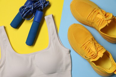Photo of Sportswear, sneakers and skipping rope on color background, flat lay