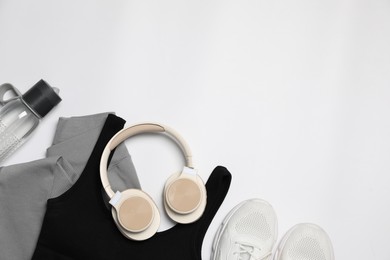 Photo of Sportswear, bottle of water, sneakers and headphones on white background, flat lay. Space for text
