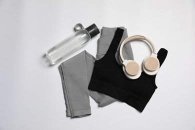 Photo of Sportswear, bottle of water and headphones on white background, flat lay