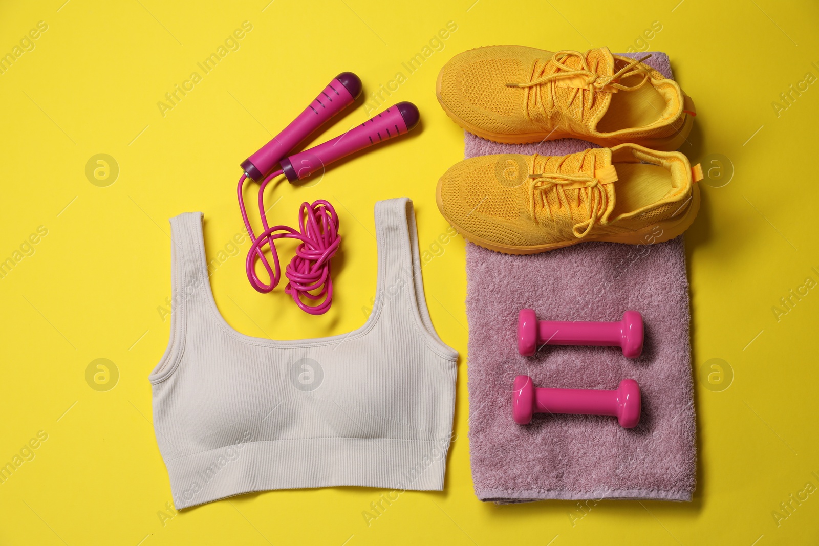 Sportswear, skipping rope, dumbbells, towel and sneakers on yellow background, flat lay Photo of Sportswear, skipping rope, dumbbells, towel and sneakers on yellow background, flat lay