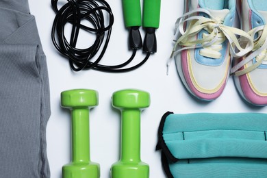 Photo of Sportswear and different gym accessories on white background, flat lay