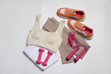 Photo of Sportswear, dumbbells, sneakers, towel and skipping rope on white background, flat lay