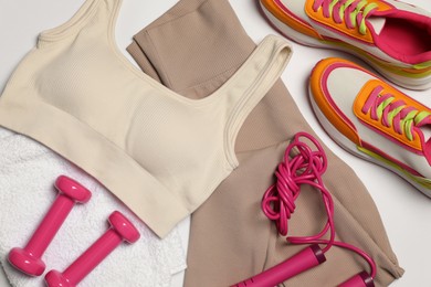 Photo of Sportswear, dumbbells, sneakers, towel and skipping rope on white background, flat lay