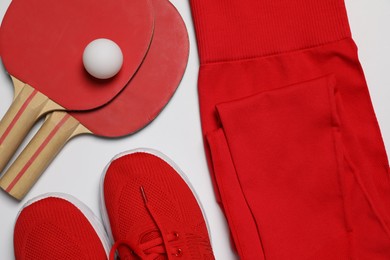 Photo of Sportswear, sneakers, ping pong rackets and ball on white background, flat lay