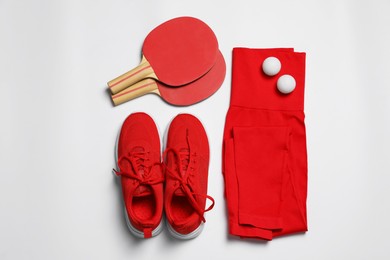 Photo of Sportswear, sneakers, ping pong rackets and balls on white background, flat lay
