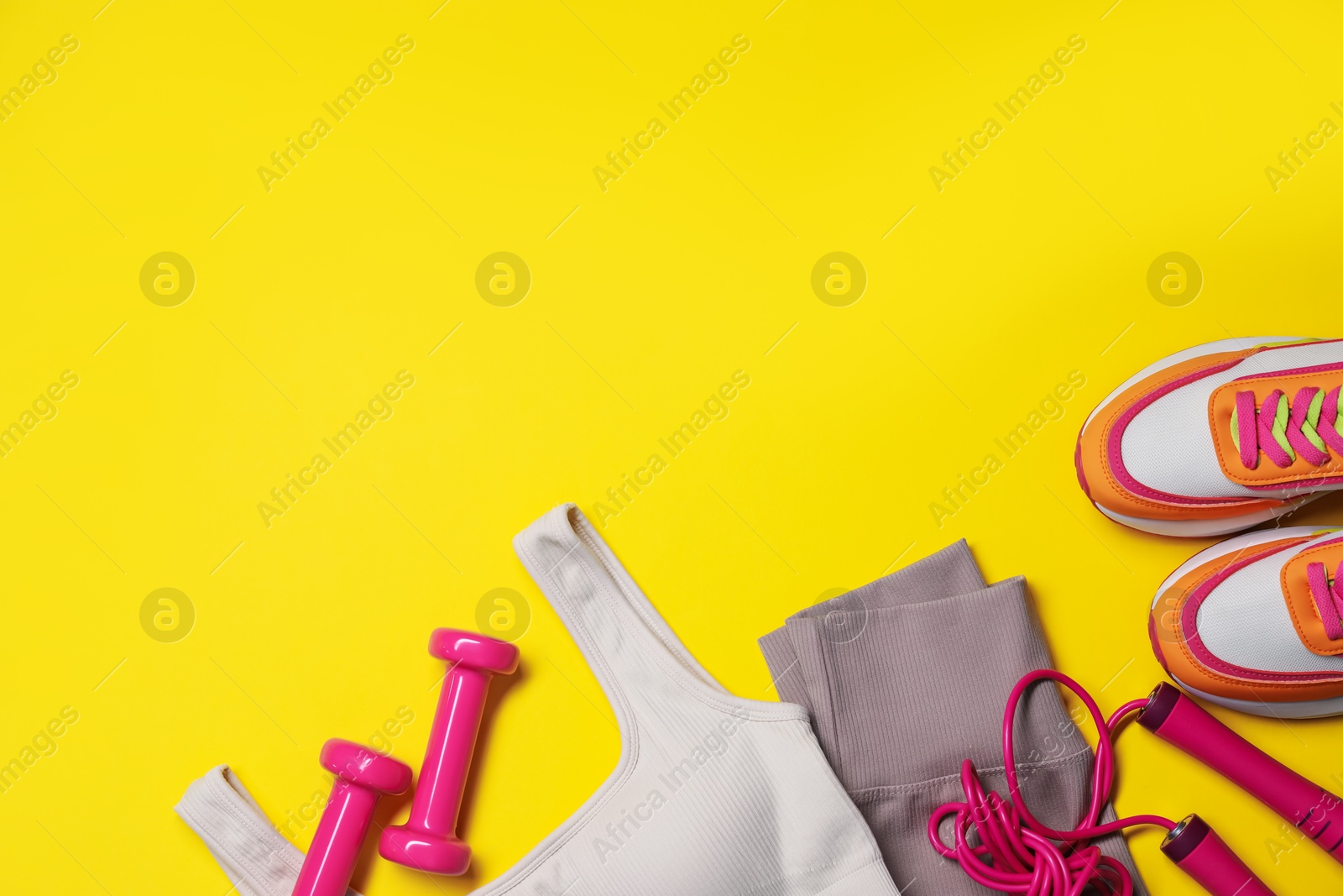 Sportswear, dumbbells, sneakers and skipping rope on yellow background, flat lay. Space for text Photo of Sportswear, dumbbells, sneakers and skipping rope on yellow background, flat lay. Space for text