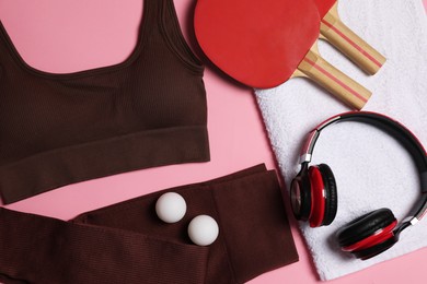 Photo of Sportswear, ping pong rackets, balls, towel and headphones on pink background, flat lay