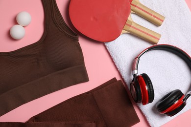 Photo of Sportswear, ping pong rackets, balls, towel and headphones on pink background, flat lay