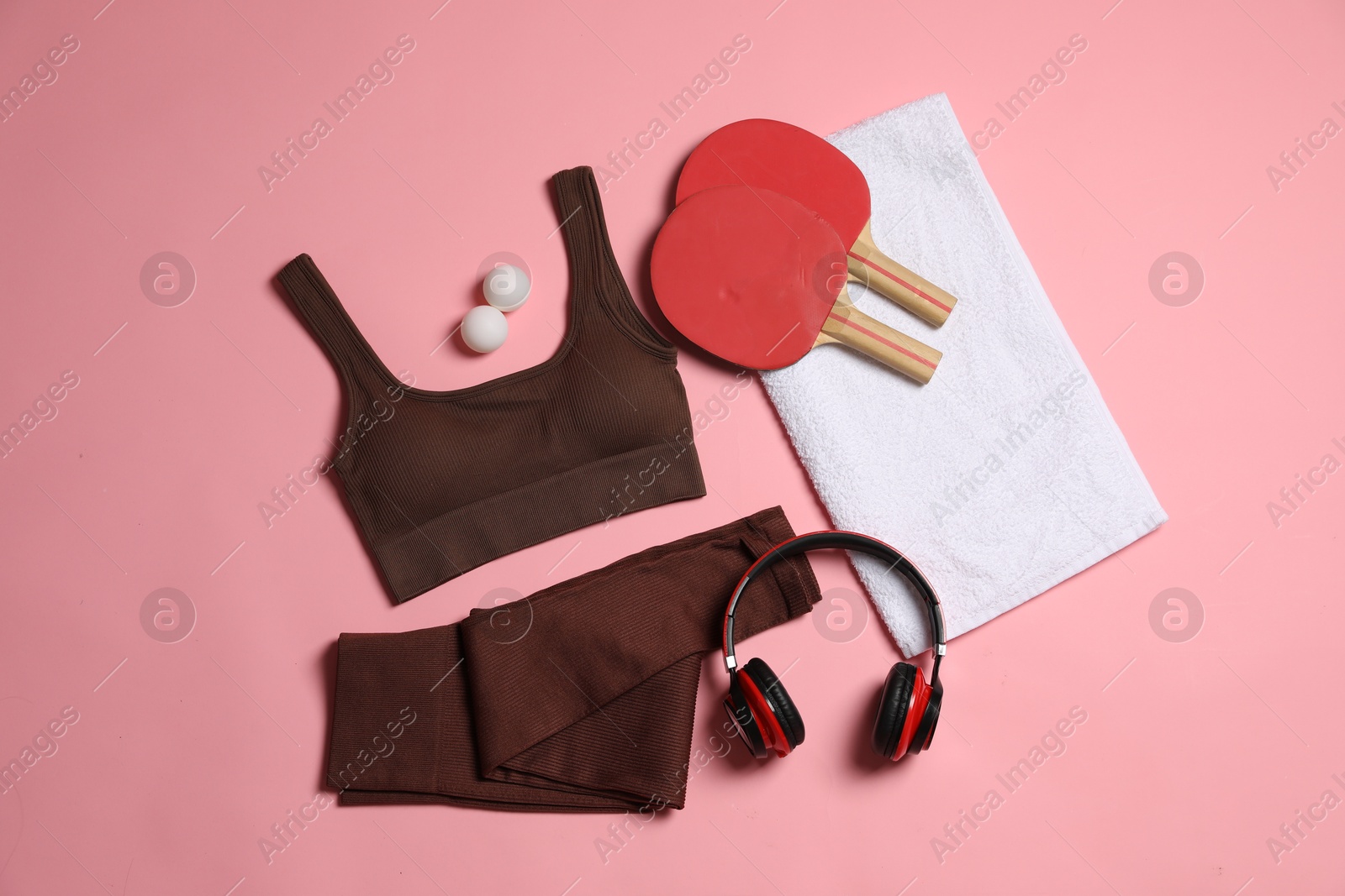 Sportswear, ping pong rackets, balls, towel and headphones on pink background, flat lay Photo of Sportswear, ping pong rackets, balls, towel and headphones on pink background, flat lay