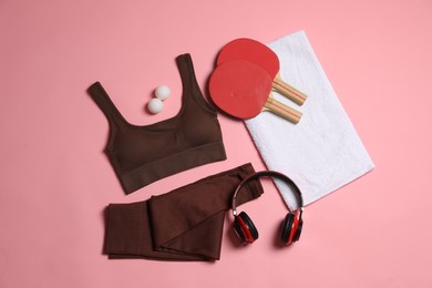 Photo of Sportswear, ping pong rackets, balls, towel and headphones on pink background, flat lay