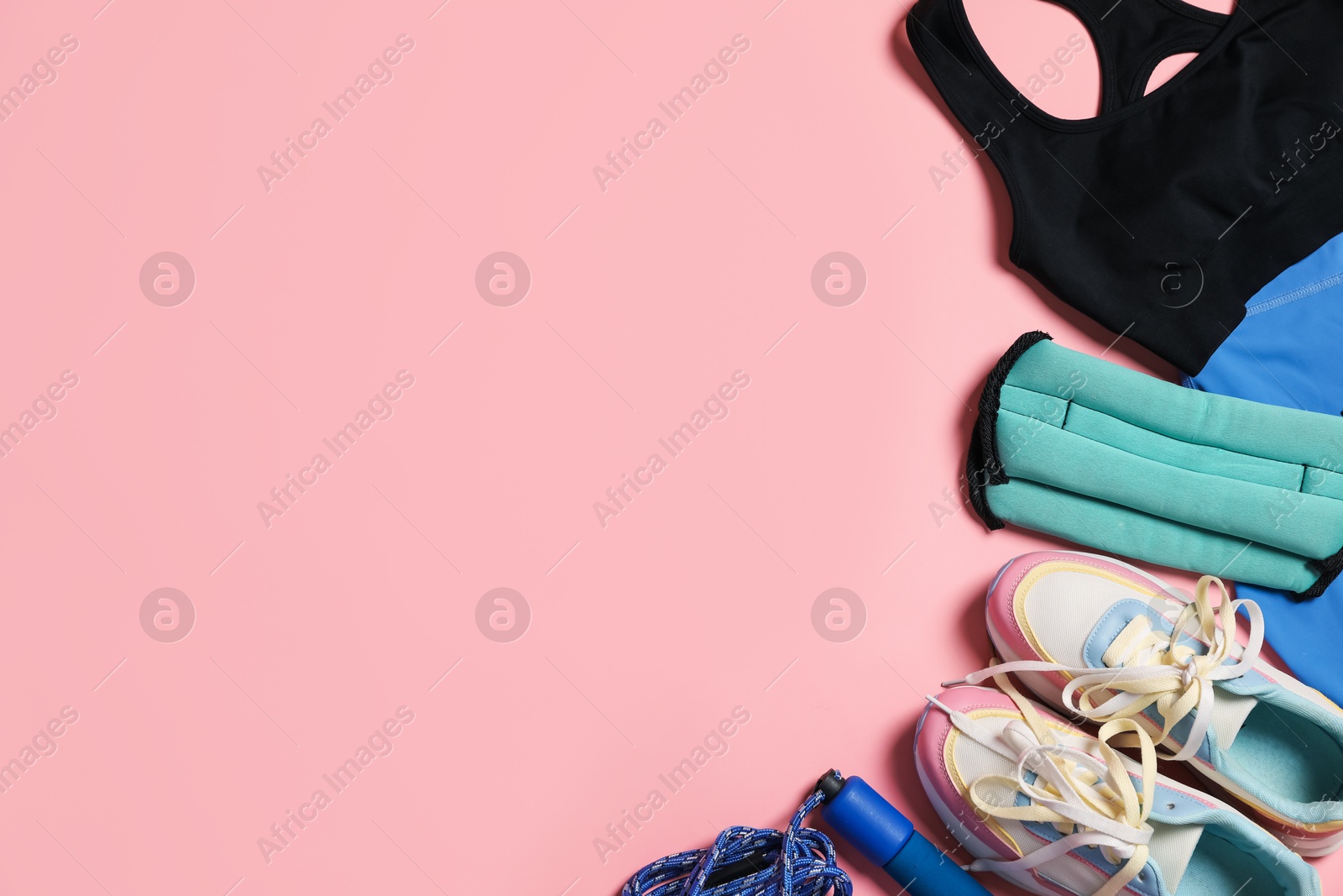Sportswear, ankle weights, skipping rope and sneakers on pink background, flat lay. Space for text Photo of Sportswear, ankle weights, skipping rope and sneakers on pink background, flat lay. Space for text