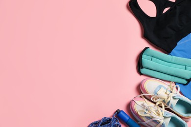 Photo of Sportswear, ankle weights, skipping rope and sneakers on pink background, flat lay. Space for text
