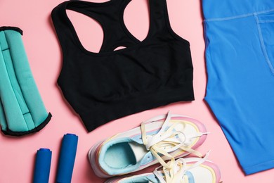 Photo of Sportswear, ankle weights, skipping rope and sneakers on pink background, flat lay