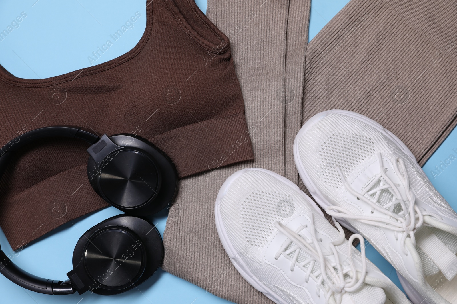 Sportswear, headphones and sneakers on light blue background, flat lay Photo of Sportswear, headphones and sneakers on light blue background, flat lay