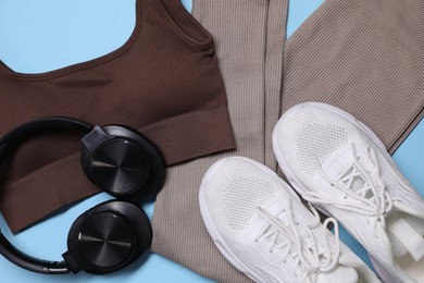 Photo of Sportswear, headphones and sneakers on light blue background, flat lay
