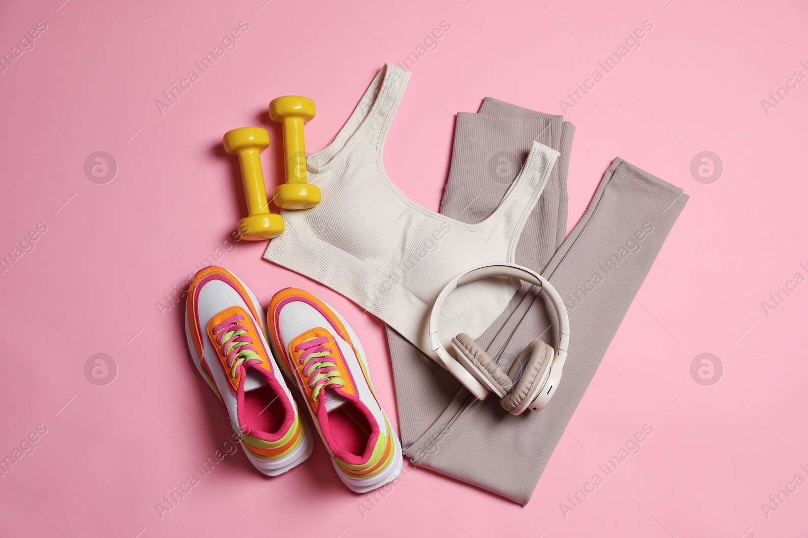Sportswear, dumbbells, headphones and sneakers on pink background, flat lay Photo of Sportswear, dumbbells, headphones and sneakers on pink background, flat lay