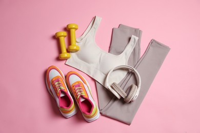 Photo of Sportswear, dumbbells, headphones and sneakers on pink background, flat lay