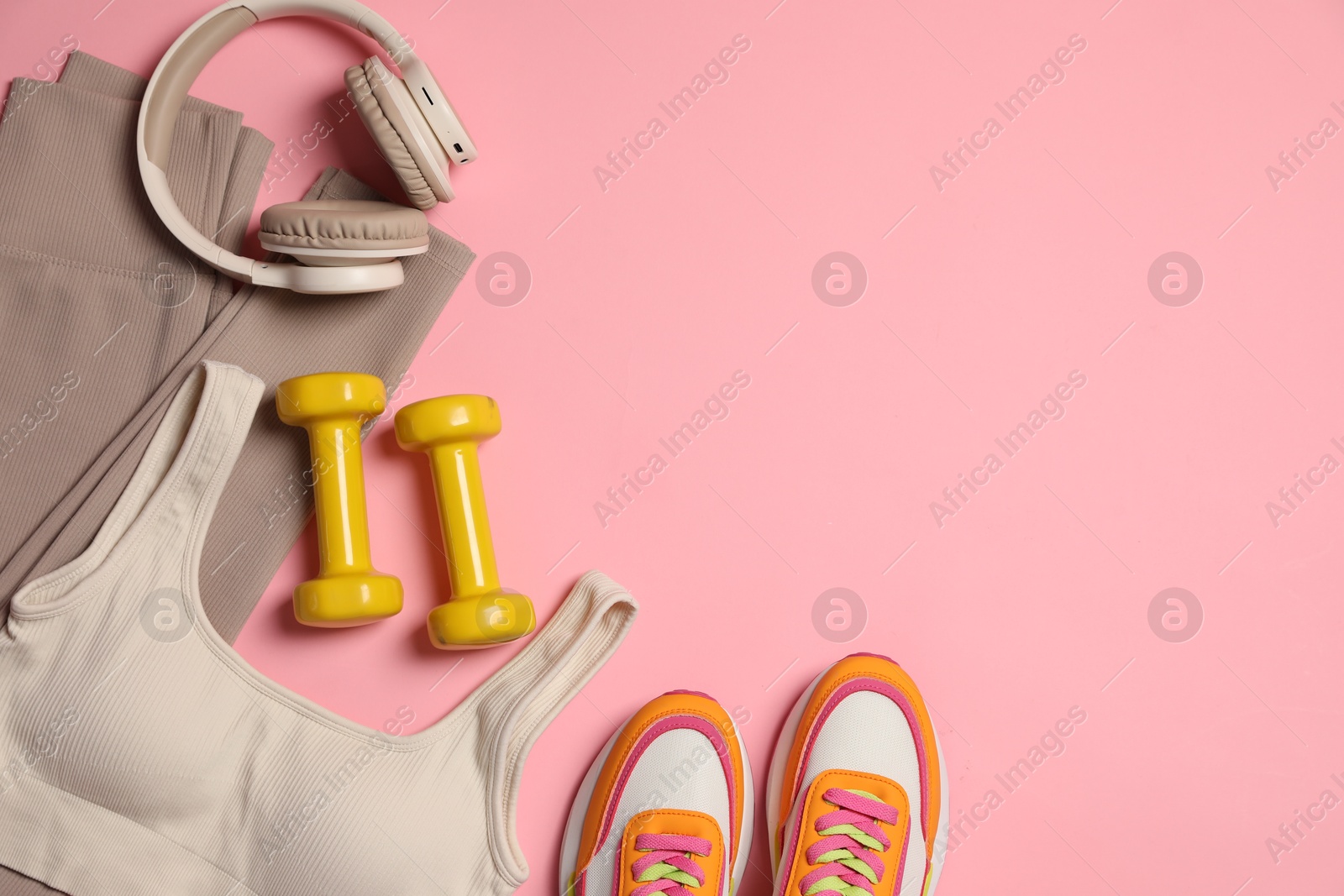 Sportswear, dumbbells, headphones and sneakers on pink background, flat lay. Space for text Photo of Sportswear, dumbbells, headphones and sneakers on pink background, flat lay. Space for text
