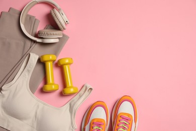 Photo of Sportswear, dumbbells, headphones and sneakers on pink background, flat lay. Space for text