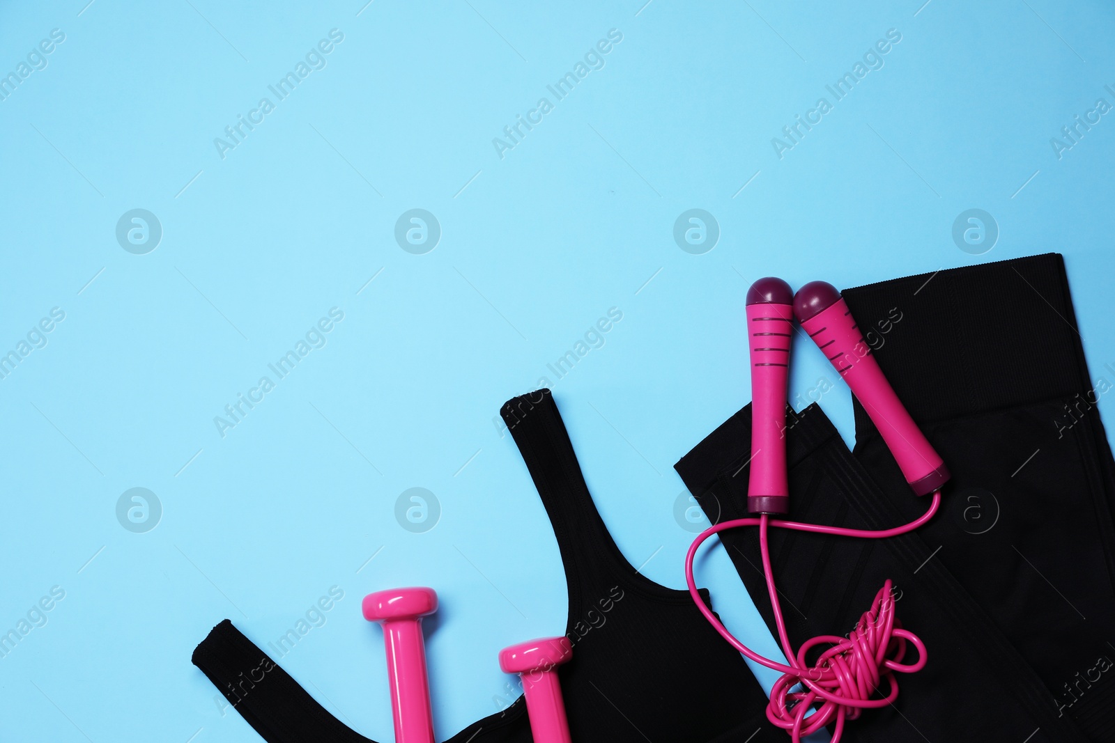Sportswear, skipping rope and dumbbells on light blue background, flat lay. Space for text Photo of Sportswear, skipping rope and dumbbells on light blue background, flat lay. Space for text