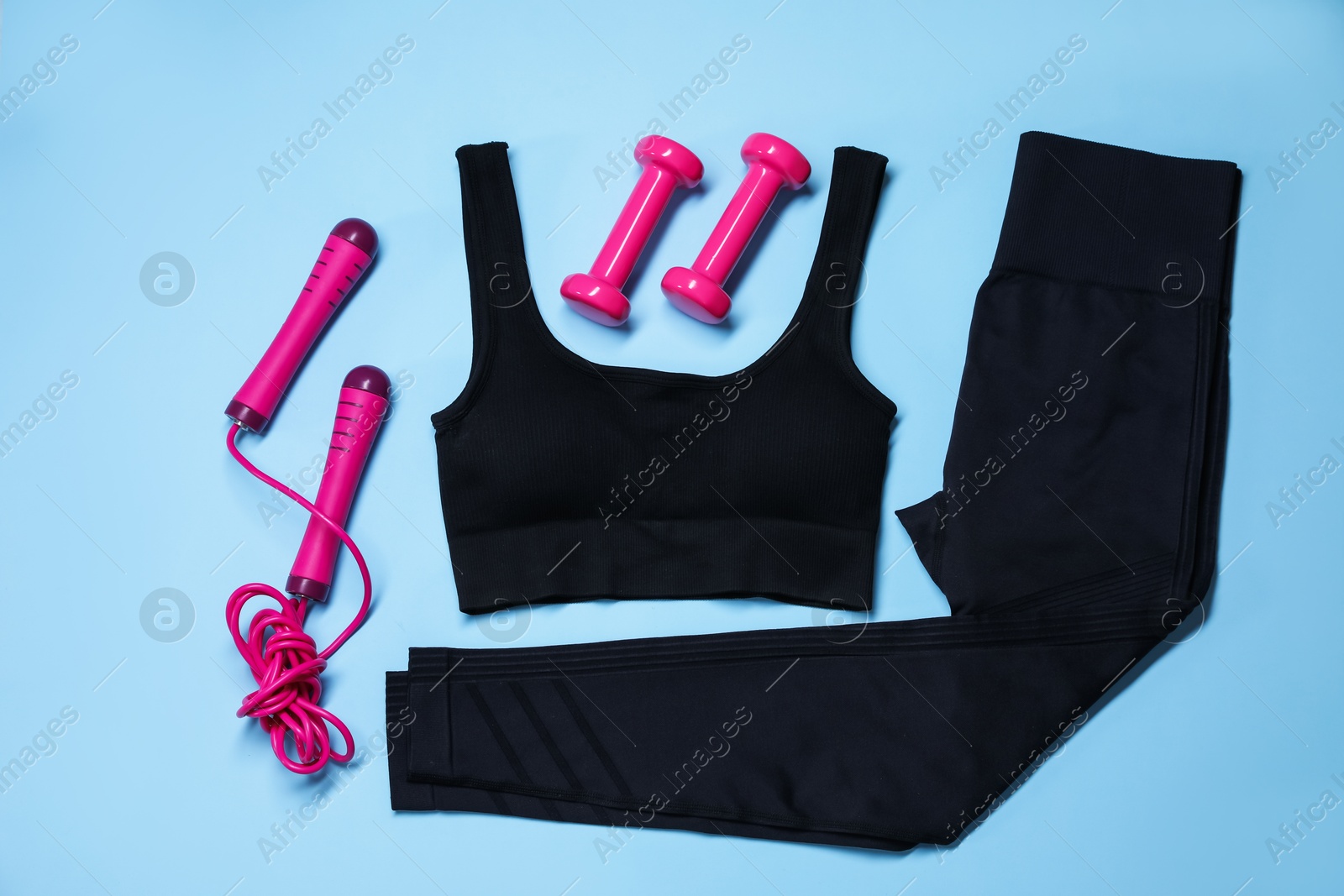 Sportswear, skipping rope and dumbbells on light blue background, flat lay Photo of Sportswear, skipping rope and dumbbells on light blue background, flat lay