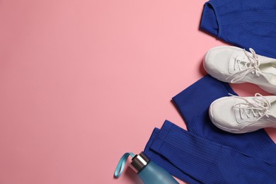 Photo of Sportswear, bottle of water and sneakers on pink background, flat lay. Space for text