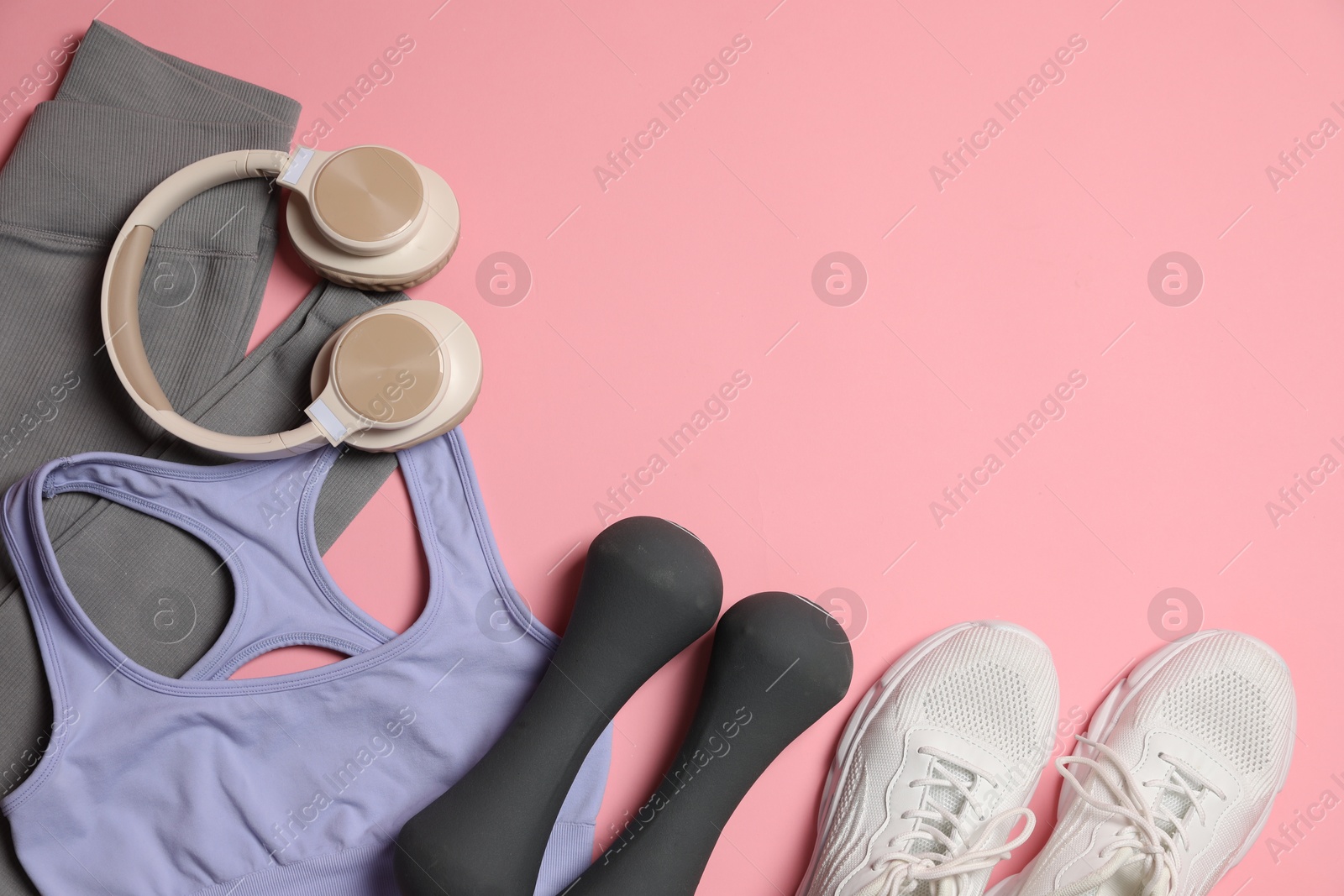 Sportswear, dumbbells, headphones and sneakers on pink background, flat lay. Space for text Photo of Sportswear, dumbbells, headphones and sneakers on pink background, flat lay. Space for text