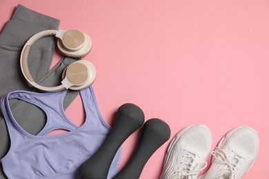 Photo of Sportswear, dumbbells, headphones and sneakers on pink background, flat lay. Space for text