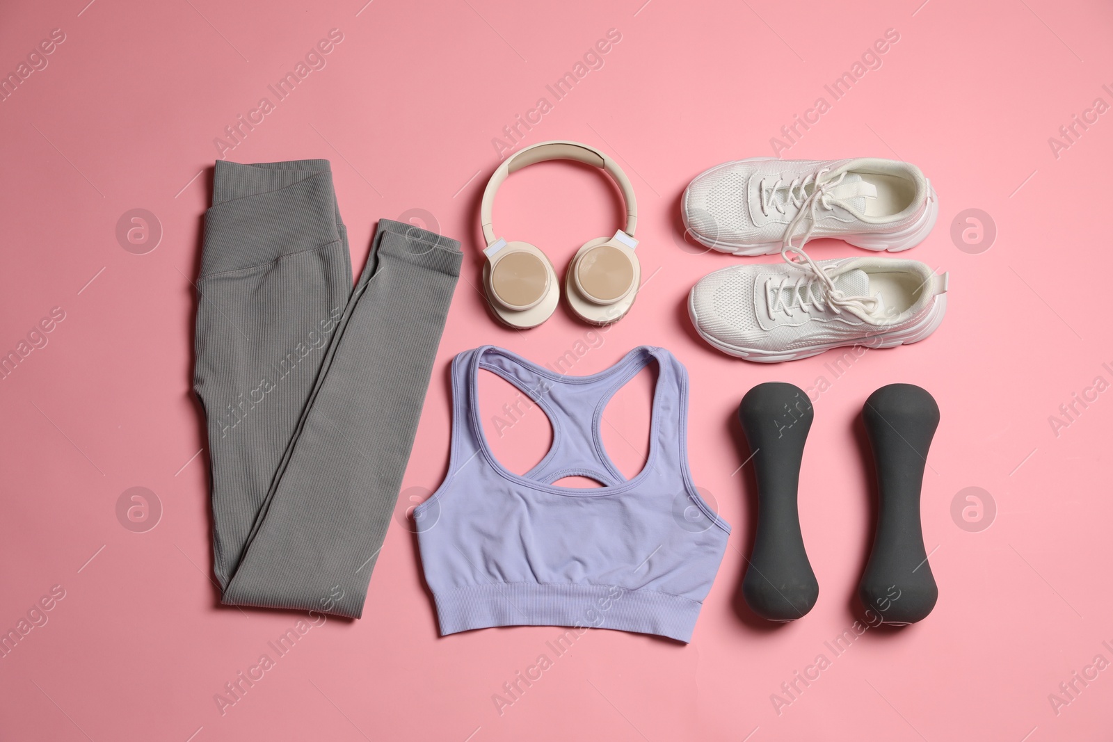 Sportswear, dumbbells, headphones and sneakers on pink background, flat lay Photo of Sportswear, dumbbells, headphones and sneakers on pink background, flat lay