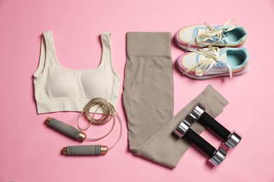 Photo of Sportswear and different gym accessories on pink background, flat lay