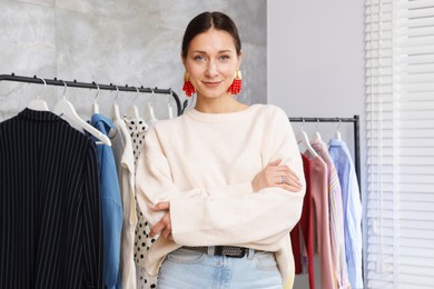 Photo of Portrait of professional stylist near clothing rack indoors