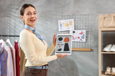Photo of Professional stylist with picture of outfit on tablet indoors
