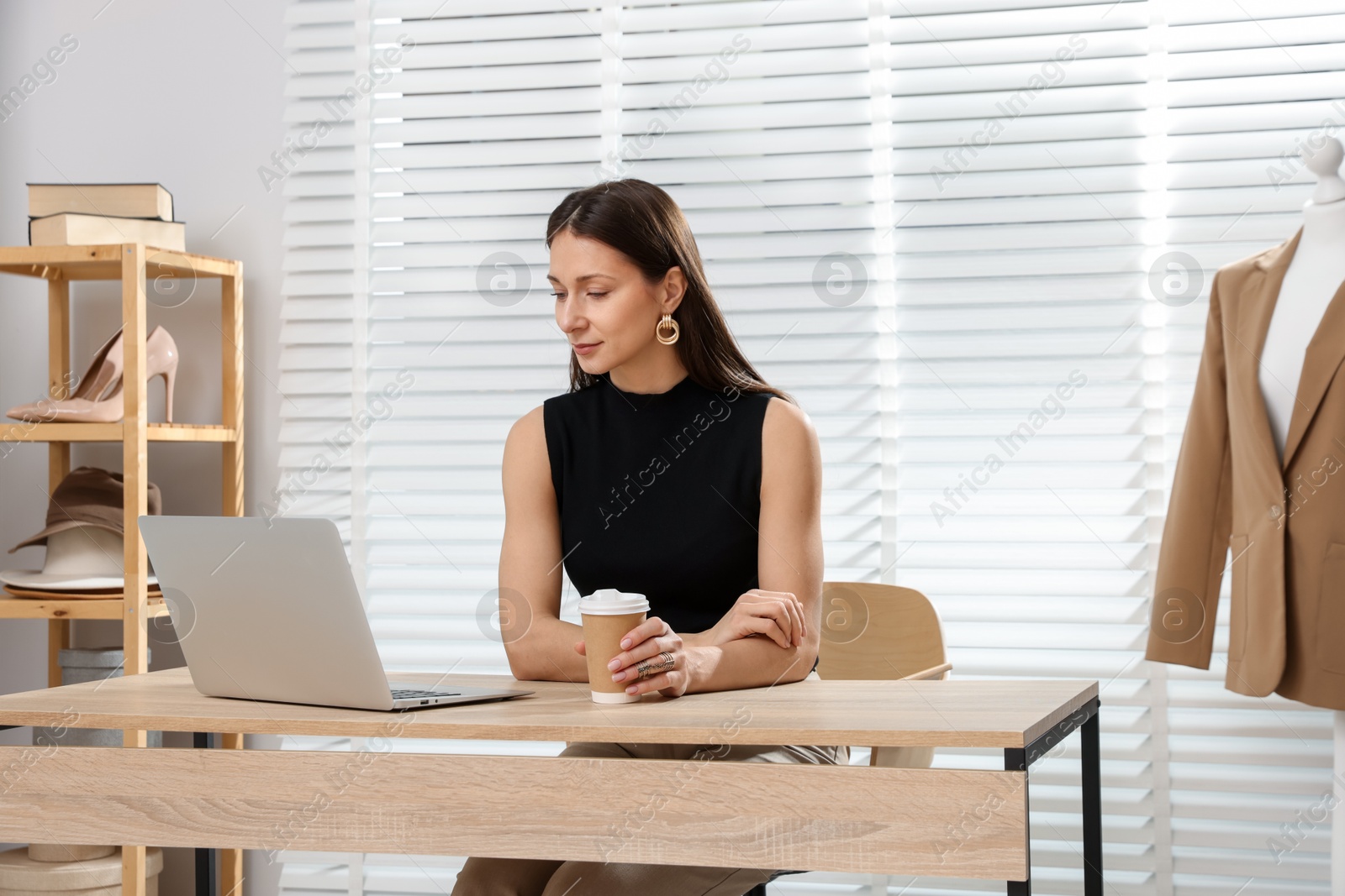 Photo of Professional stylist having online consultation with client via laptop at desk indoors