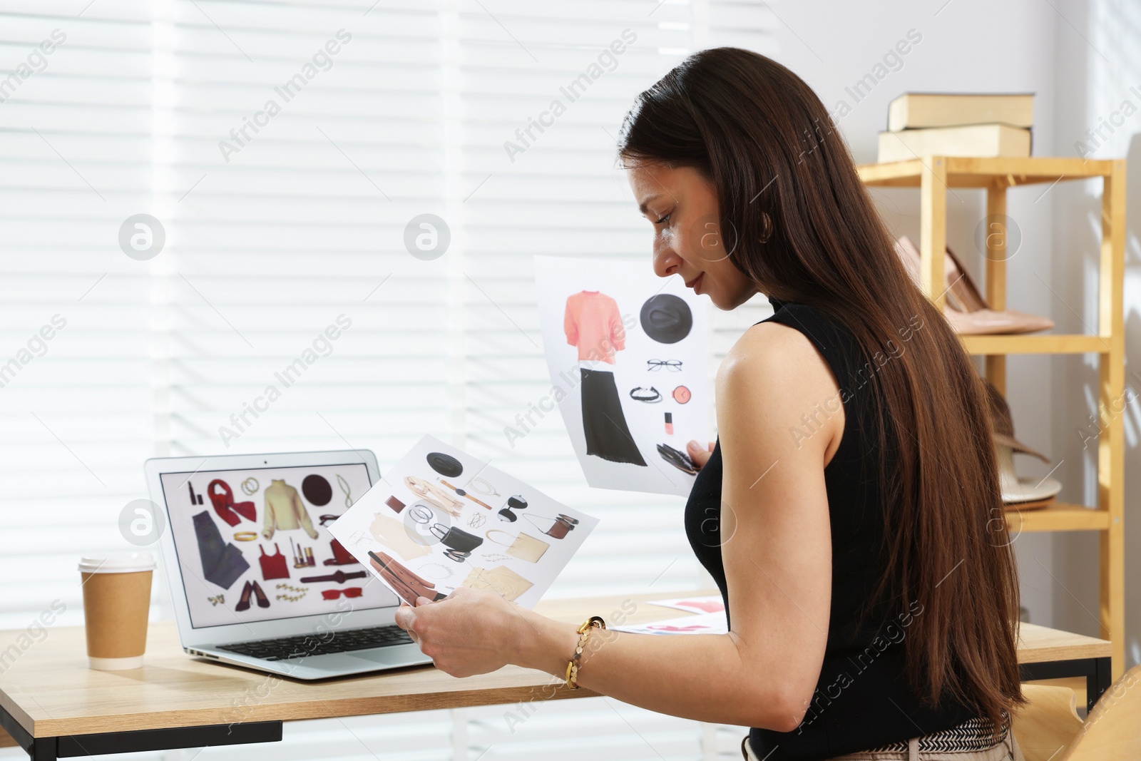 Professional stylist making collage with outfit on laptop at desk indoors Photo of Professional stylist making collage with outfit on laptop at desk indoors