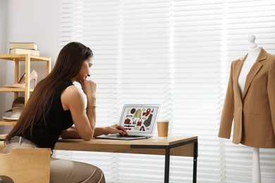 Photo of Professional stylist making collage with outfit on laptop at desk indoors